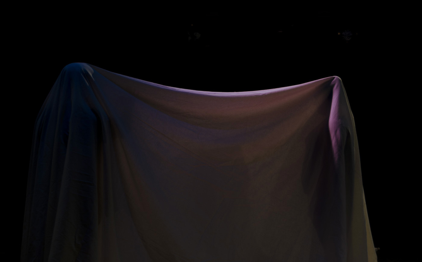 A long sheet of fabric that looks to be held up by two tall long objects. The fabric is lit with blue and pink lights.