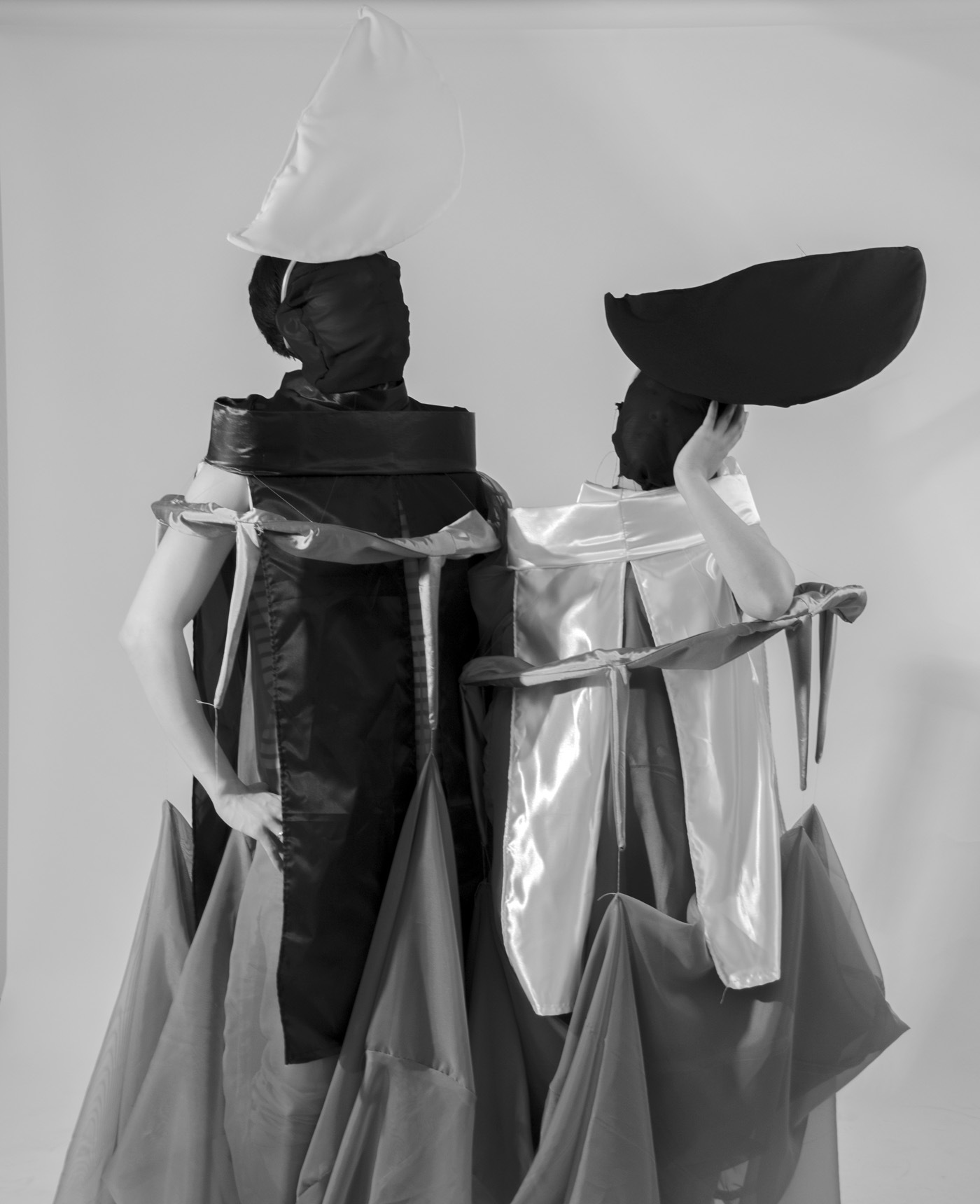0:00 is the culmination of the entire ANDROGYNE collection. Two figures stand joined by fabric—one wearing white and the other wearing black. Each wears a hat with half-moon on top. It represents the intersection between the two traditionally recognized genders and proposes a joining of them to create an androgyne identity.