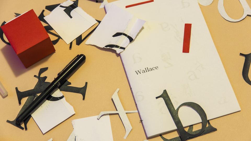 a photo of various scraps of paper and cut-outs of the typeface Wallace. There is a brush pen, and a booklet with the words "Wallace" on it.