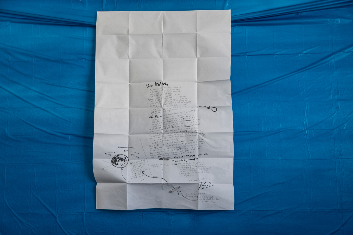 Large white piece of paper with a long handwritten note against a plastic blue background.