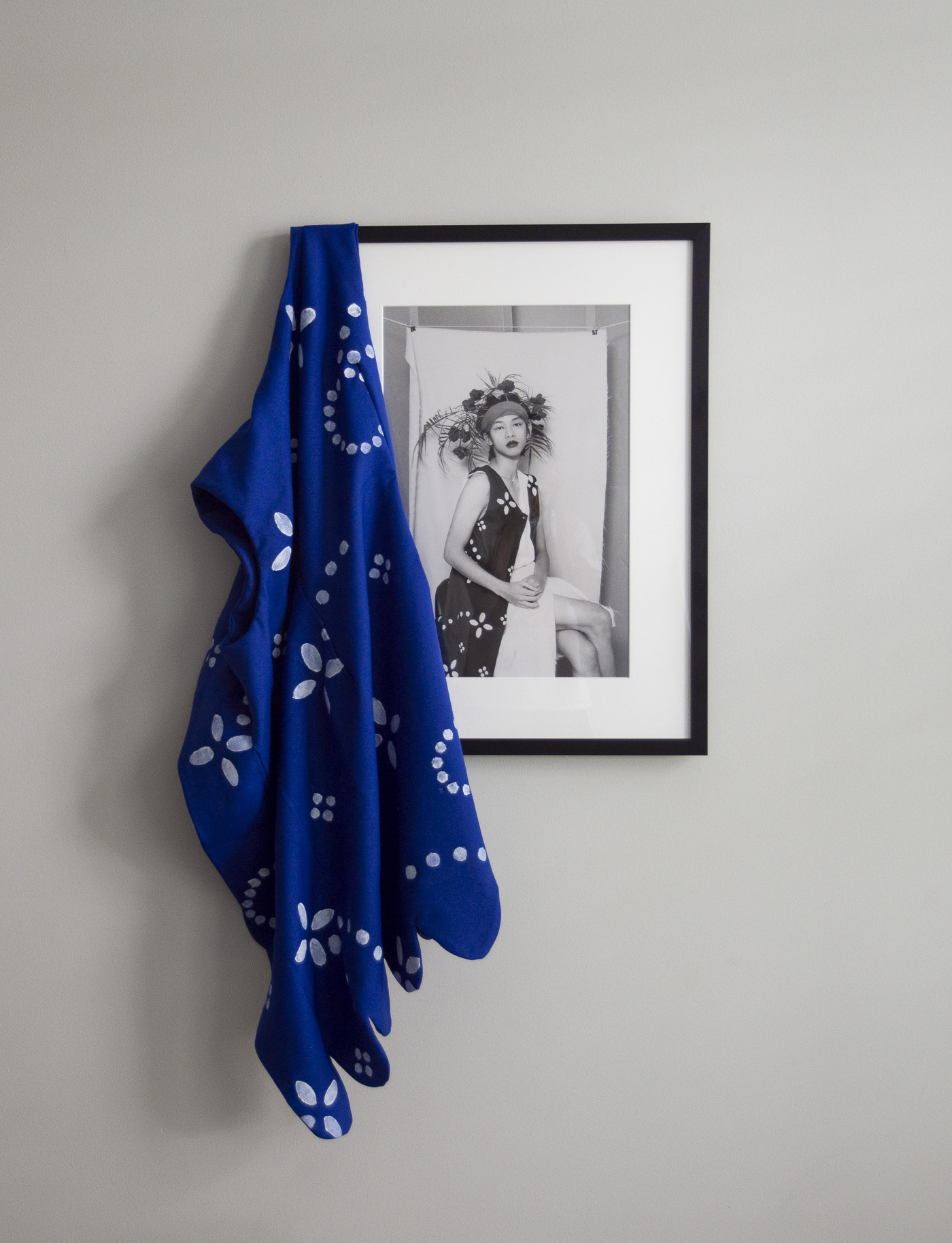 a black and white photograph hung against a wall with a blue garment draped on it