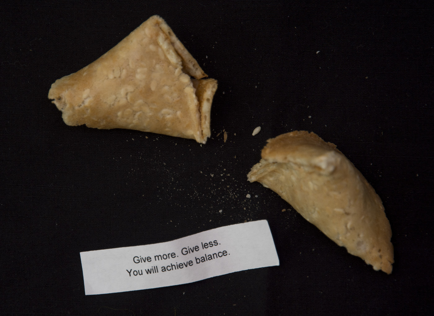 broken fortune cookie with the fortune reading "Give more. Give less. You will achieve balance"
