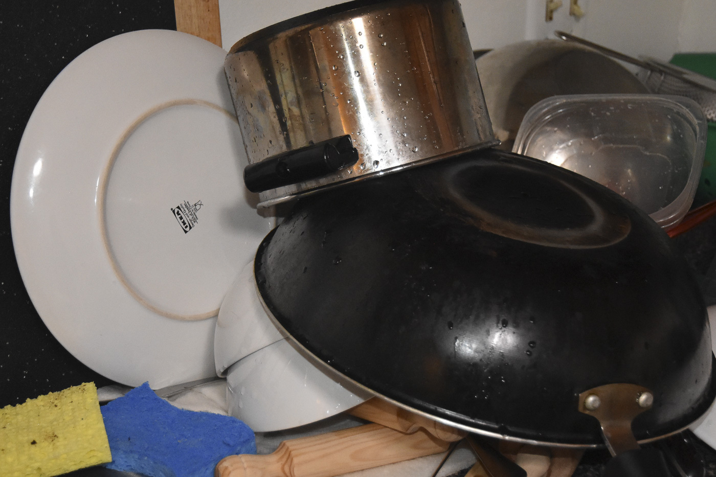 a pile of pots, pans, plates, and a wok