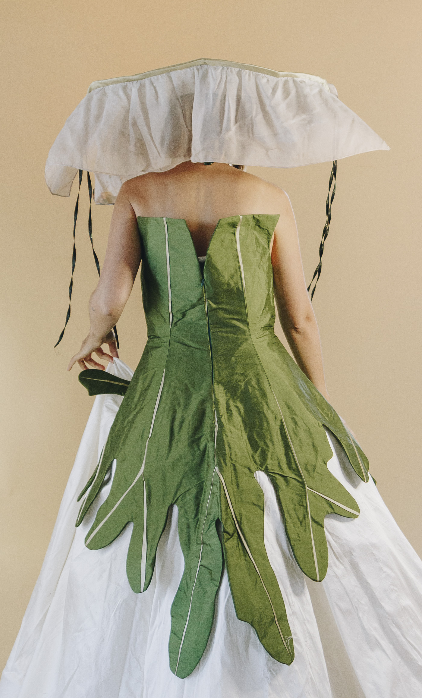 The back of Crystal's green leaf-inspired dress. There is gold fabric sewn as veins of the leaf