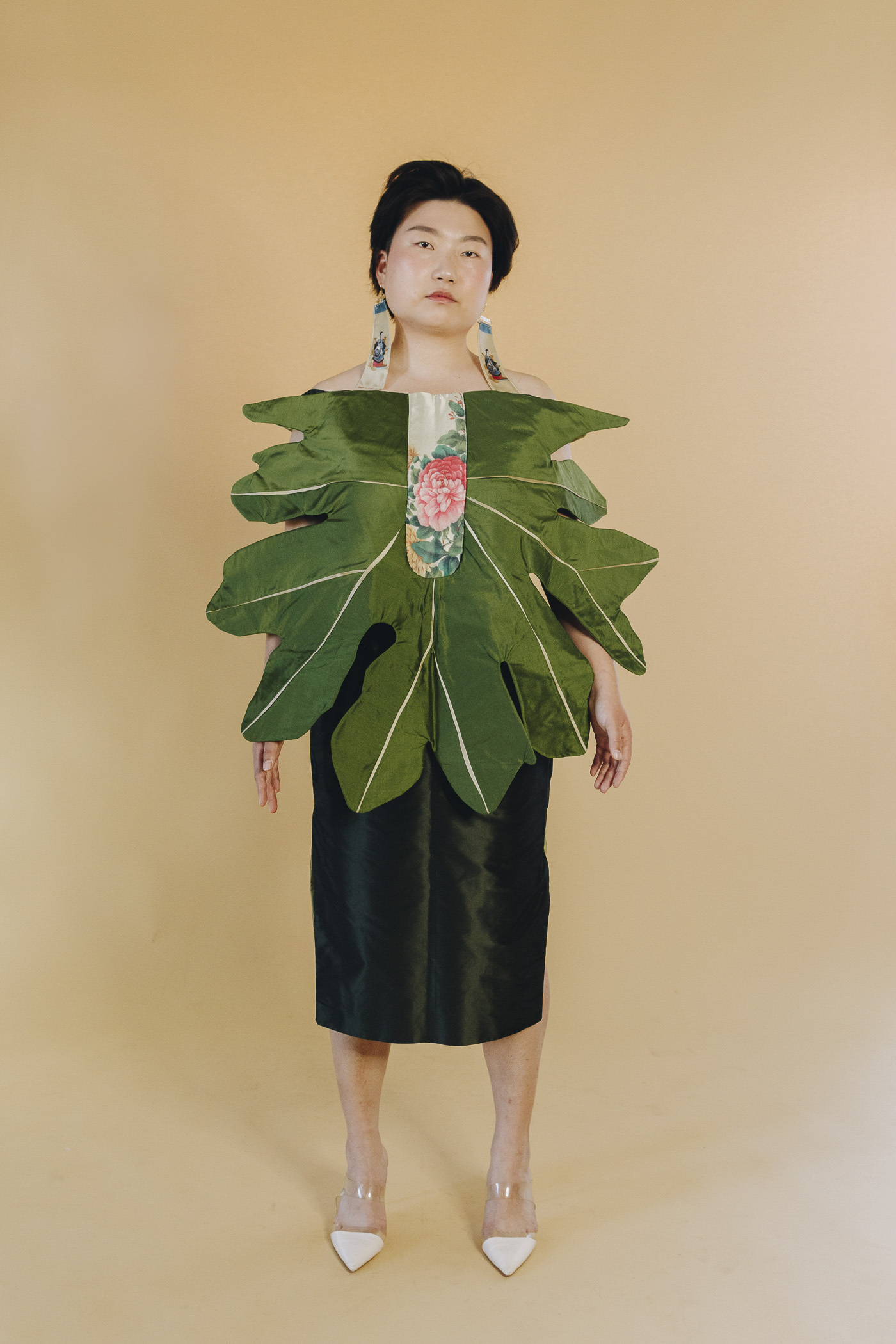 Dahn Bi wears a green dress with a large green leaf radiating out of the center