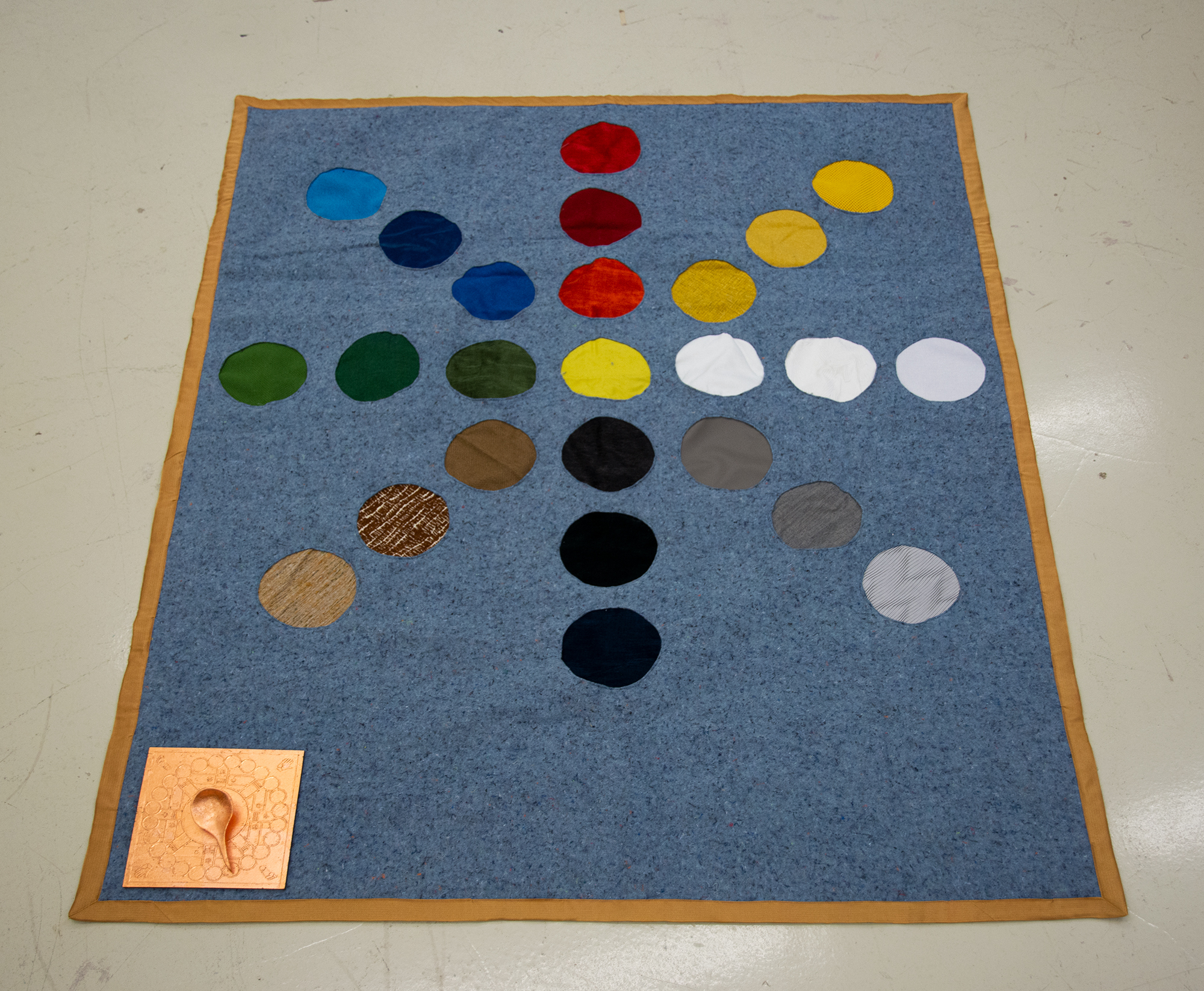 a large mat made of a felt moving blanket. Circles in various colors radiate out evenly spaced from the center.