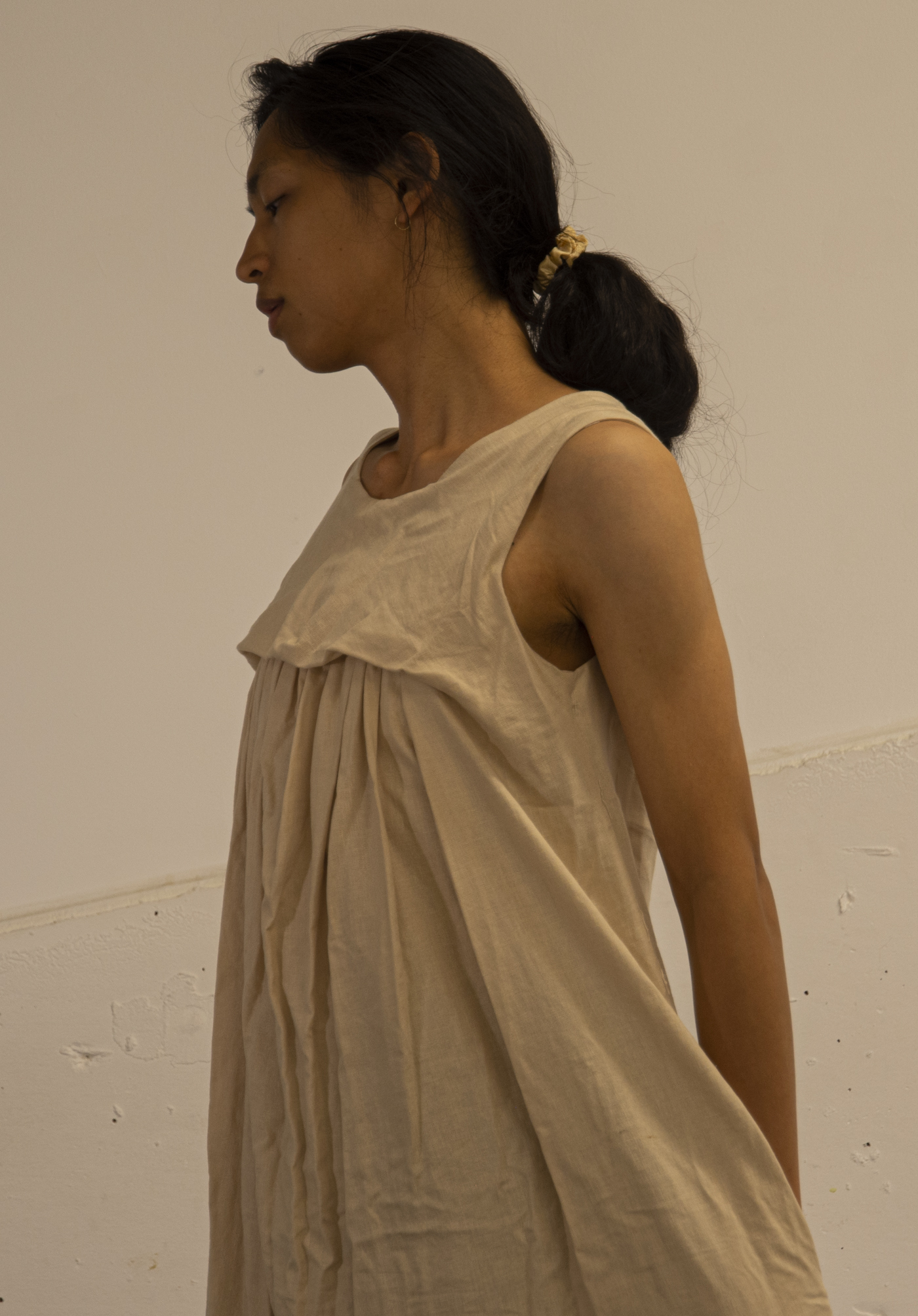 The artist wears a dress that is gathered across the chest.