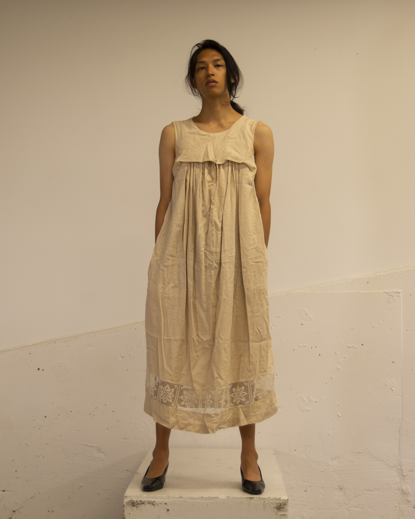The artist stands wearing a dress.