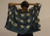 The artist wears a hand-dyed rectangular draped top made using itajime block-resist dyeing techniques.