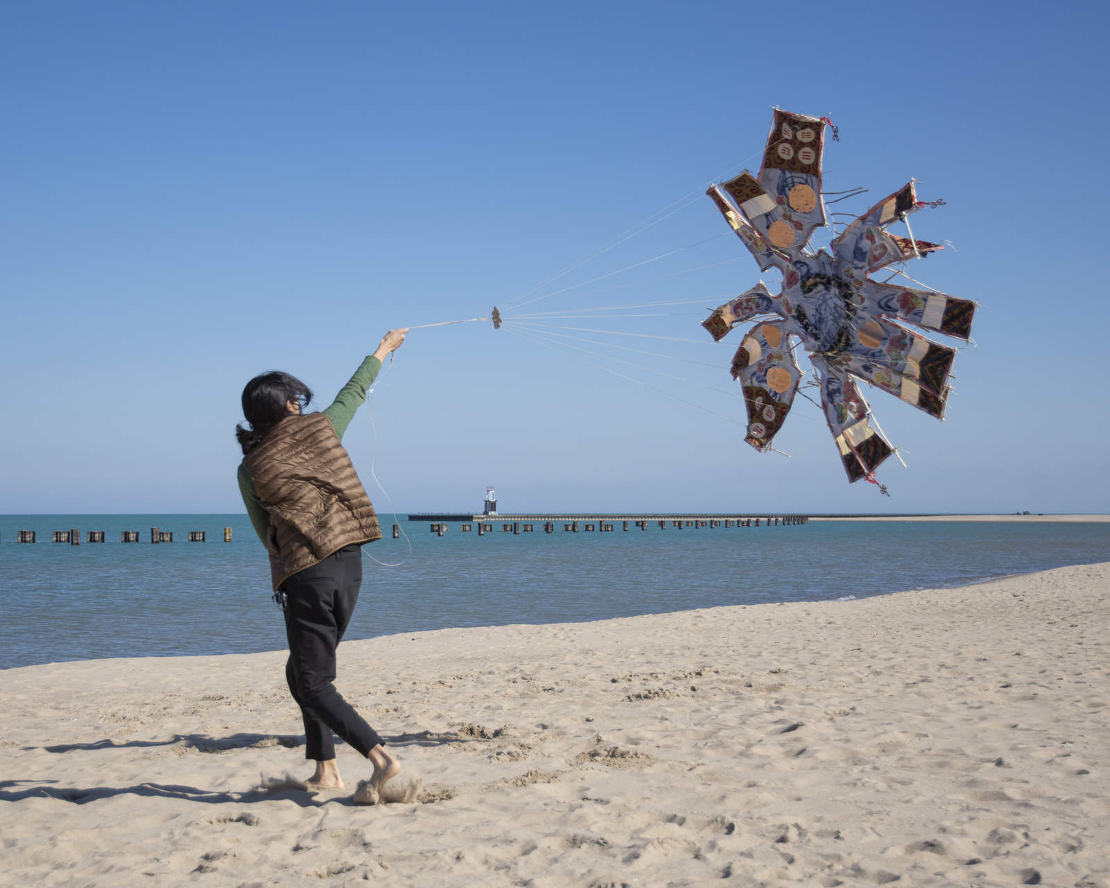 The artist is on a beach flying a kite. The kite does not fly very well.