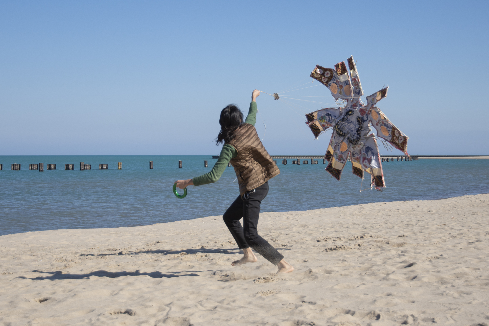 The artist is running on the beach desperately trying to get their so-called kite to fly.