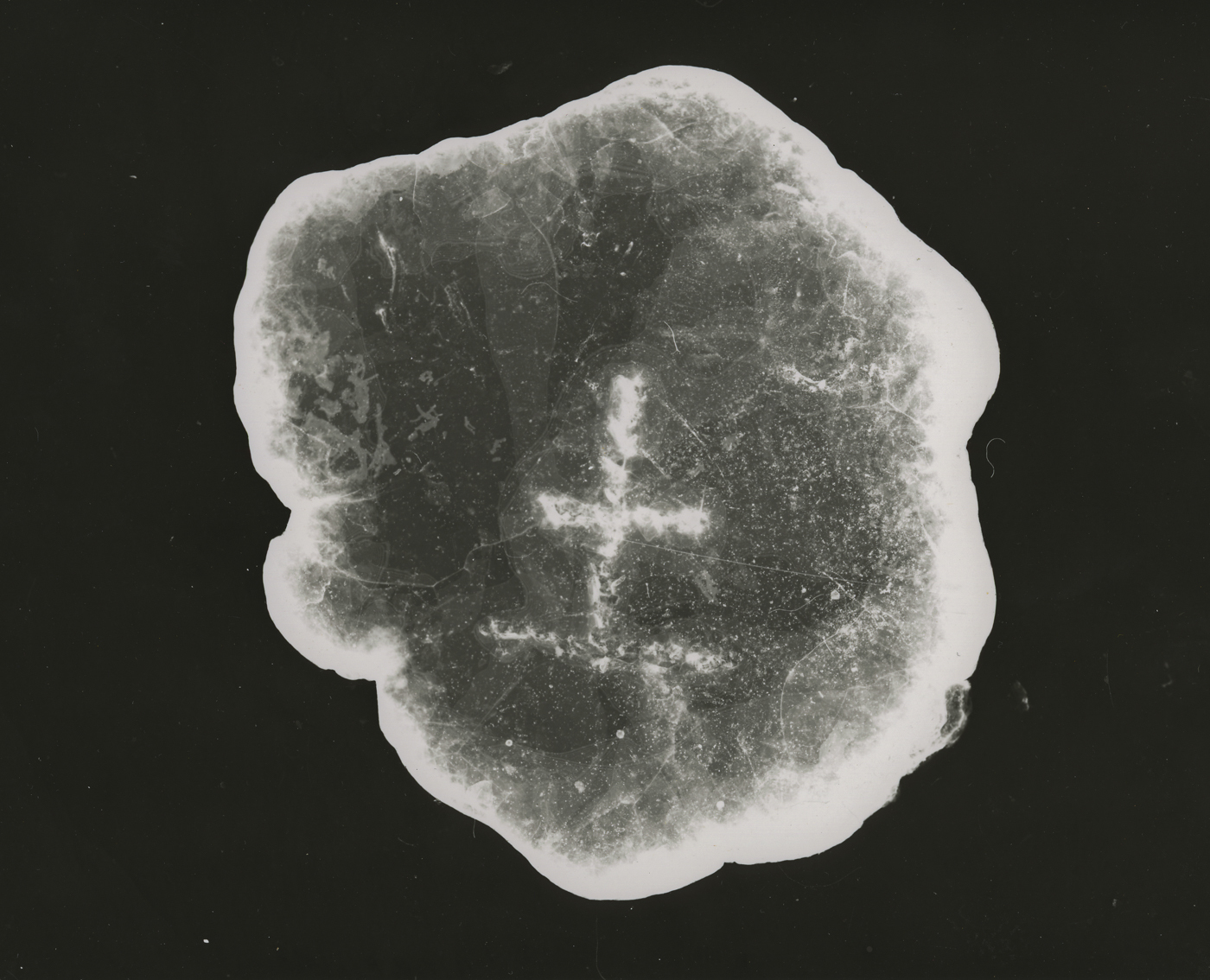 A black and white photographic enlargement of a piece of mica that has a Chinese character etched into it.